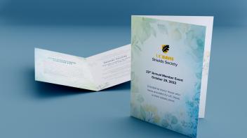 Two bi-fold Shields society invitation cards sitting on a blue surface.